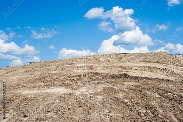 Obraz Sandy dirt hill with tracks against clouds and sky