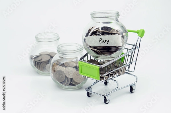 Obraz Coins in small container and shopping cart with label Buy - fina