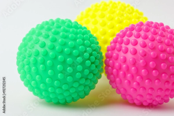 Fototapeta Dog is playing with spiky ball and other toys. medical child sport concept. game of ball with colored balls on a white . a dog playing a game of ball with colored balls on a white lifestyle.