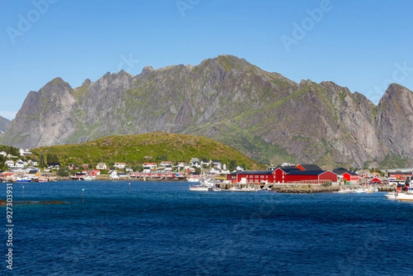 Fototapeta Set of red houses on the coast with green mountains in the background