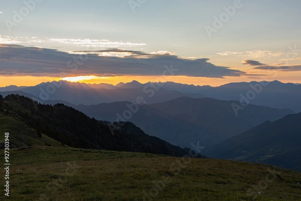 Fototapeta Sunrise with sun rays between the clouds and mountain ranges around