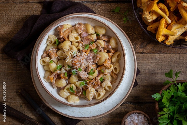 Fototapeta Pasta with chanterelles, bacon and cheese in plate on wooden table, top view, selective focus