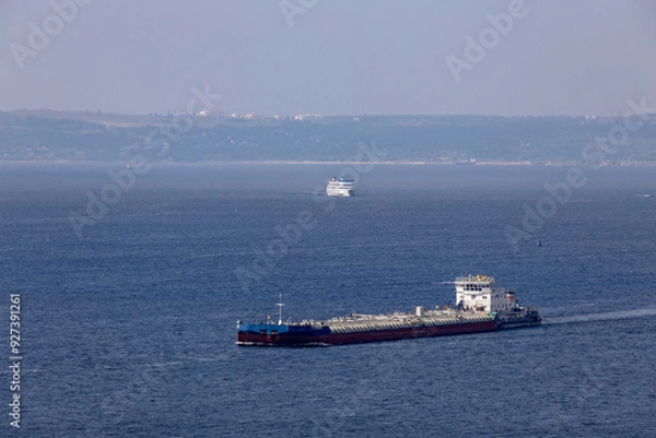 Fototapeta Navigation on the Volga River. A tanker barge in the foreground, a cruise ship in the background.