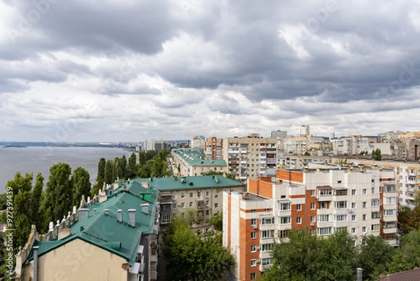 Fototapeta View of the city and the Volga River embankment from a height. A summer day, clouds in the sky. The city of Saratov, Russia