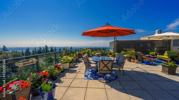 Fototapeta Umbrella casting a wide shadow on a large rooftop patio garden on a bright summer day.