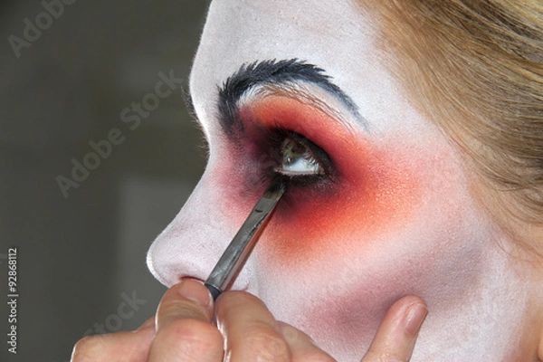 Fototapeta Applying of bright helloween makeup using white, red and black c