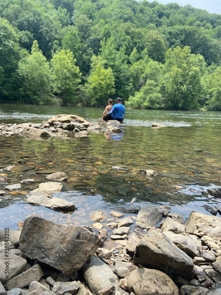 Fototapeta Dad and Son sitting on a rock at the river