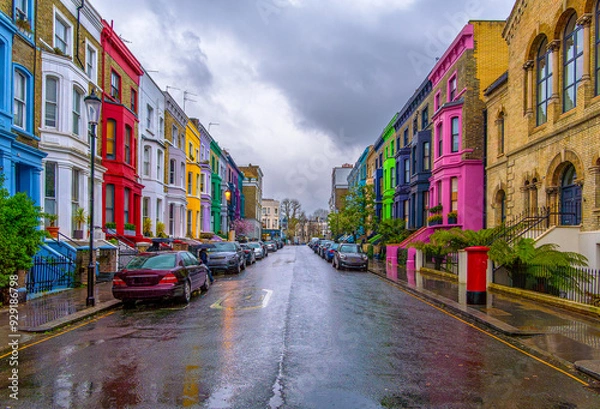Obraz View of the wonderful Lancaster Road, the mythical street of colorful houses under a fine rain with a cloudy sky and pedestrians walking with umbrellas in Notting Hill, London, England.