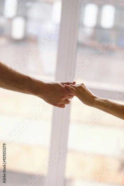 Fototapeta Close-up view of couple holding hands indoors. Man and woman take each other hands, love and family concept, selective focus