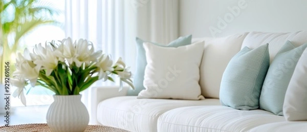 Fototapeta  A white couch holds a vase of white flowers Another vase, likewise filled with white blooms, sits beside it