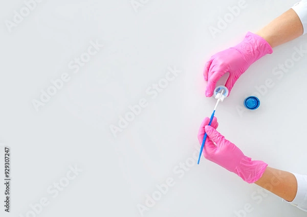 Obraz A special brush for taking and microscopic examination of cells from the surface of cervix and cervical canal. Close-up of the doctor's hands in pink gloves in process of work
