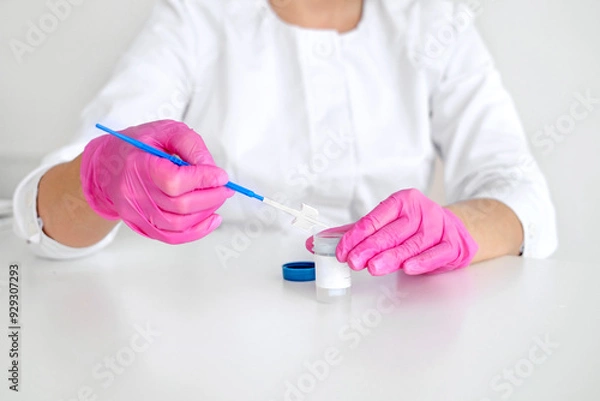 Obraz A gynecologist in pink gloves with a brush for taking a swab from the cervical canal for cytological abnormalities