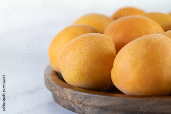 Fototapeta Ripe apricots on a wooden plate, close-up. Fresh natural apricots, delicious summer dessert, emphasis on detail, close-up, high resolution.