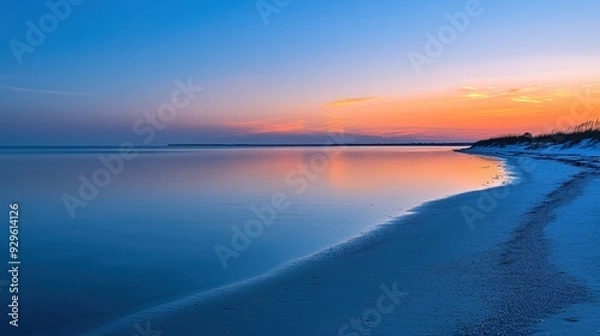 Fototapeta A serene beach at sunset, showcasing calm waters and a colorful sky.