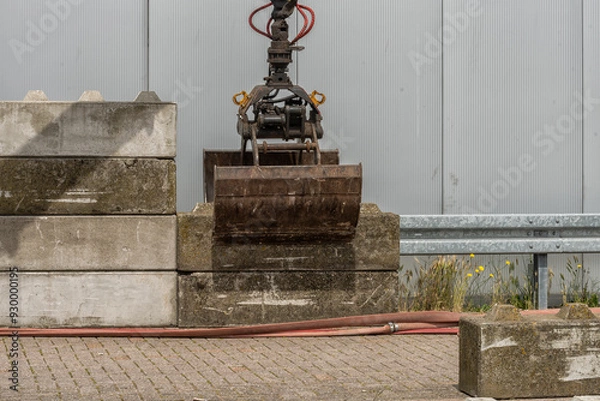 Fototapeta steel sorting grab of an excavator lifts a concrete block