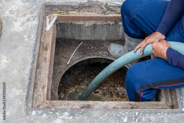 Obraz A man is carrying a suction hose from the Waste Water Treatment Plant to the suction truck.