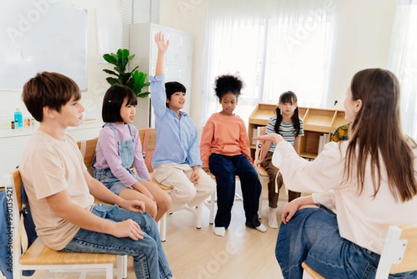 Obraz Multicultural primary school children participate in engaging group lesson. Teacher facilitates active learning through circular seating arrangement, encouraging student involvement and communication