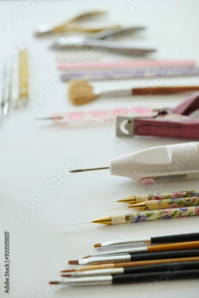 Fototapeta Various artistic tools, such as paintbrushes and decorative pens, displayed neatly on white background These tools may be used for painting, drawing, and other creative activities