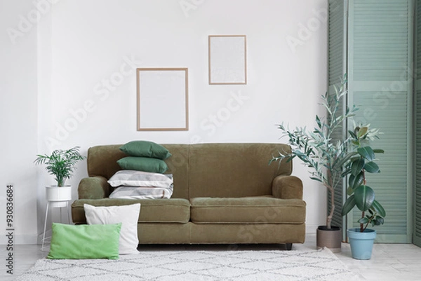 Fototapeta Interior of living room with stack of pillows on green sofa