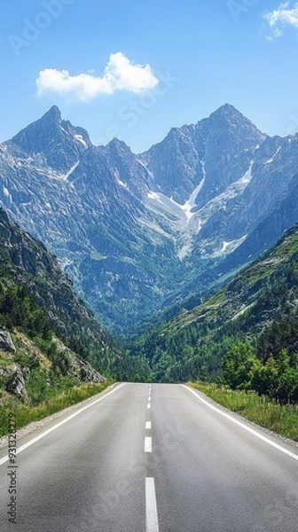 Obraz A scenic road winds through majestic mountains under a clear blue sky, perfect for adventure and exploration.