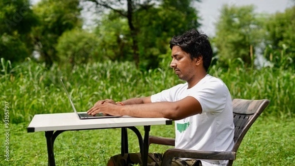 Obraz Indian young boy doing work from home. Man sitting on office table at garden doing work on internet