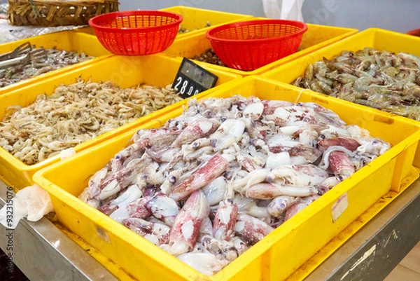 Obraz Seafood assortment in an Asian supermarket. Fresh squid and shrimp of different sizes in plastic boxes for self-service.