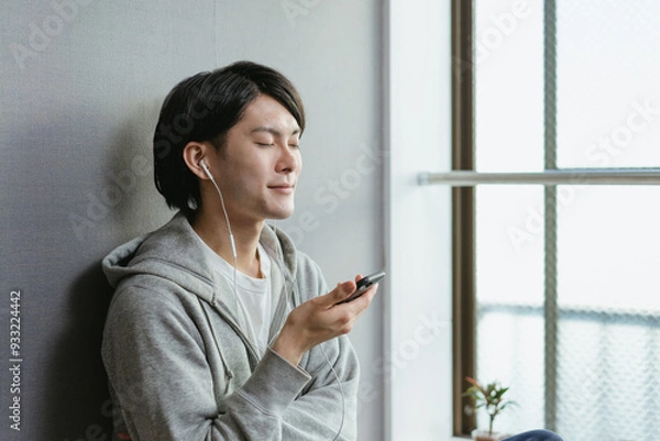 Obraz 月額の音楽を楽しむ若い男性・サブスクやユーチューブ動画を見る