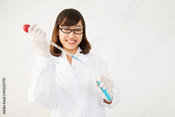 Fototapeta 試験管にピペットで試薬を注ぐ白衣を着た若い女性