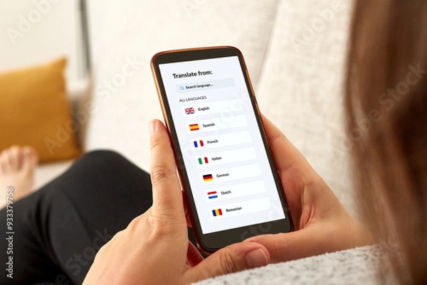 Fototapeta Close up photo of a girl on a sofa using language translator app with mobile smartphone.