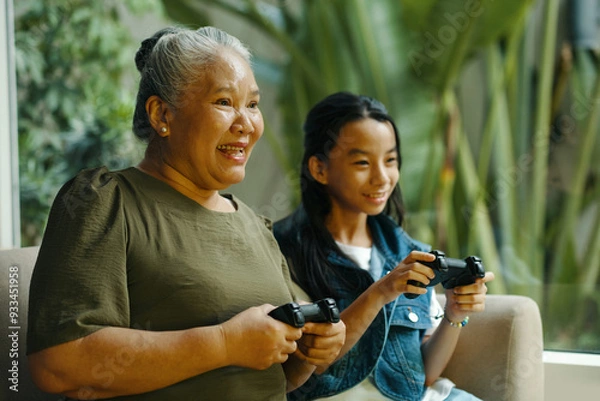 Fototapeta Grandma playing console with her grandchild during their leisure time at home