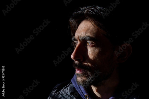 Obraz rostro lateral con mirada seria de hombre sobre fondo oscuro 