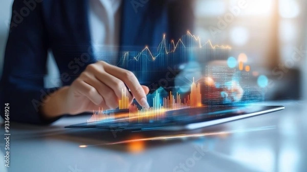 Fototapeta Professional analyzing financial data on a tablet with digital graphs and charts illustrating market trends and insights.