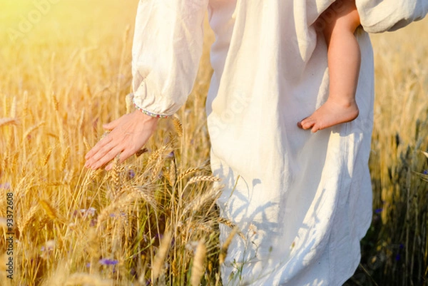 Fototapeta Picture of mother with child holding hand above wheat field on