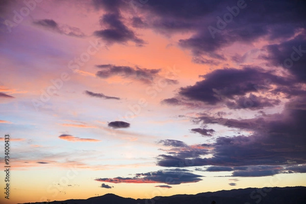 Fototapeta The sky is filled with clouds and the sun is setting, creating a beautiful