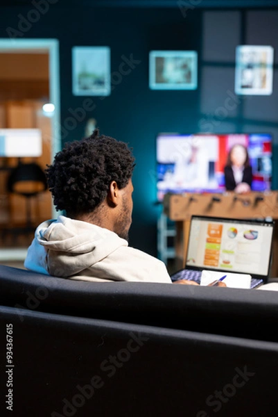 Fototapeta BIPOC person working in personal office, checking statistical data financial graphs on laptop screen. Freelancer in apartment living room comparing business graphic economic numbers