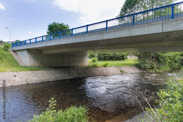 Fototapeta Reinforced concrete road bridge over the river. Close-up during sunny day in summer. Aerial view on a bridge across a small river. Canal or ditch with green grass meadow, Underneath of classic style 