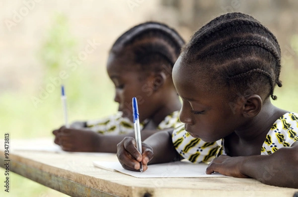 Obraz Afrykańskie dzieci w szkole odrabiania lekcji. Afrykańscy uczniowie pochodzenia etnicznego piszą swoje wypracowania w afrykańskiej szkole. Siedząc przy biurku trzymają niebieskie długopisy, aby spisywać swoje prace domowe.