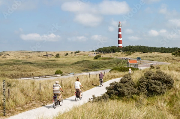 Fototapeta Seniorzy jeżdżący na rowerach po wydmach Ameland w pobliżu latarni morskiej w Holandii