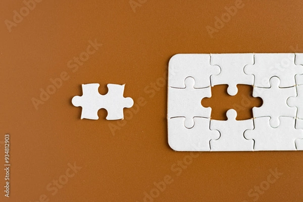 Fototapeta Top view of unfinished jigsaw puzzle on chocolate brown background. Business concept.