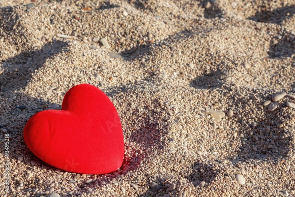 Fototapeta Red heart on the beach with small pebbles  background.