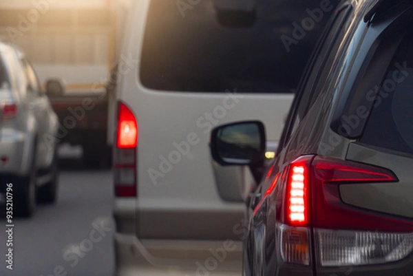 Fototapeta Rear side of car on the aspahlt road. Transtport of car turn on brake light in the business time environment of moring time. Traffic congestion and queues of cars.