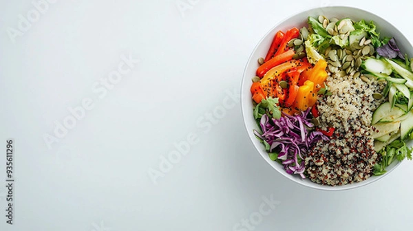 Fototapeta a fresh salad bowl filled with colorful vegetables, quinoa, and seeds, placed on a clean, white surface.