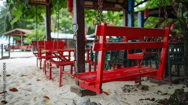 Fototapeta cozy red swing on chains instead of chairs in the outdoor restaurant of the resort town