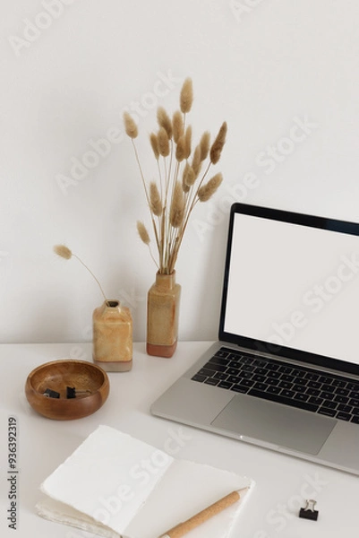 Fototapeta Open notebook with stationary, vases with dried flowers and laptop on the white desk. Back to school minimalistic modernt still life. Screen mock up for your text or image.