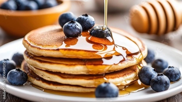 Fototapeta Professional photo of Close-up of pancakes gently drizzled with honey and garnished with blueberries. Aesthetic food backdrop