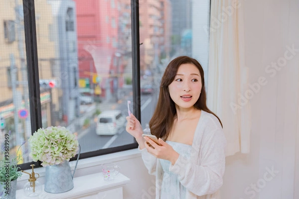 Fototapeta 歯磨きをしながら携帯電話を操作するパジャマ姿の女性
