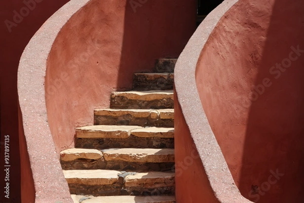 Obraz Vue d'un détail de l'escalier de couleur orangée de la maison des esclaves de l'île de Gorée au Sénégal. Rampe de forme incurvée. Architecture coloniale. Bâtiment rénové et coloré. Avril 2024.