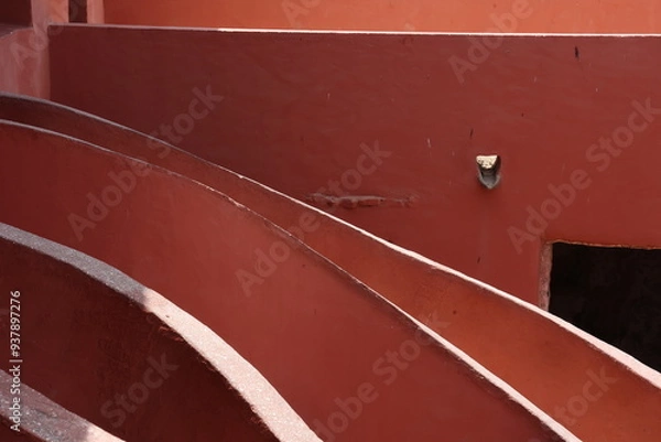 Obraz Vue d'un détail de l'escalier de couleur orangée de la maison des esclaves de l'île de Gorée au Sénégal. Rampe de forme incurvée. Architecture coloniale. Bâtiment rénové et coloré. Avril 2024.