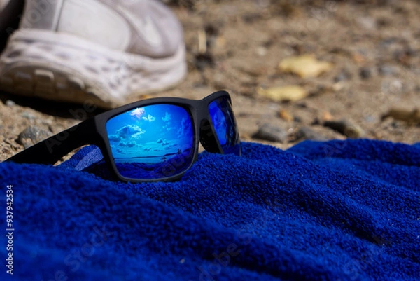Fototapeta blue reflection in sunglasses by the beach on a lue towel