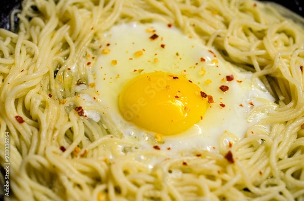 Fototapeta Delicious scrambled eggs with pasta and seasonings cooked in a hot cast iron skillet